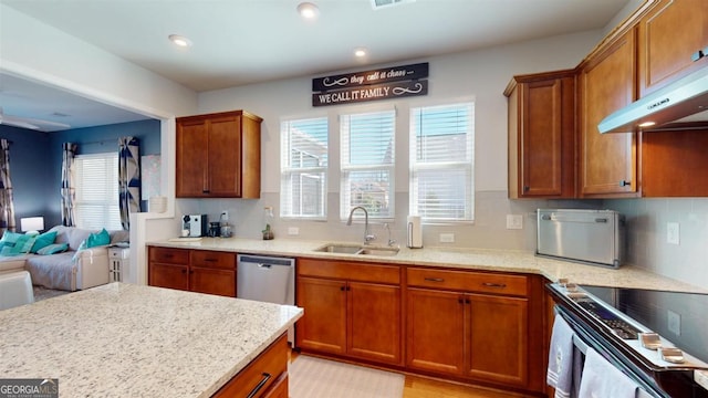 kitchen with appliances with stainless steel finishes, sink, tasteful backsplash, and light stone countertops