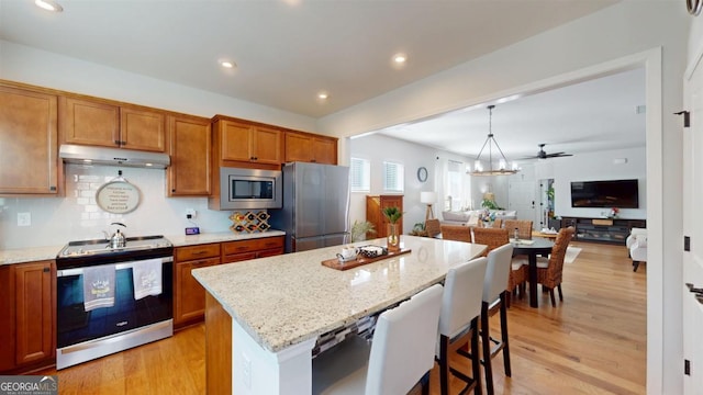 kitchen featuring a kitchen island, light wood-type flooring, stainless steel appliances, and pendant lighting