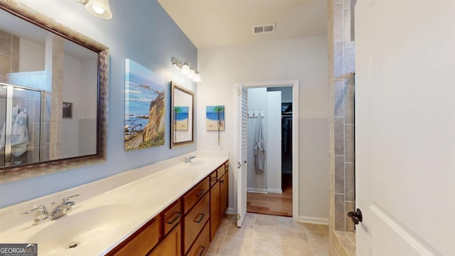 bathroom with vanity, a tile shower, and tile patterned floors