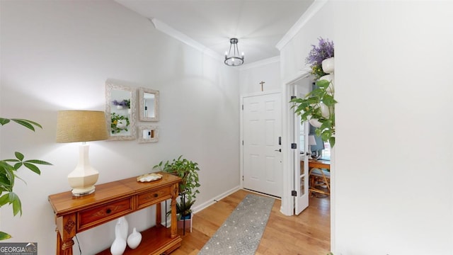 entryway with light hardwood / wood-style flooring, crown molding, and an inviting chandelier