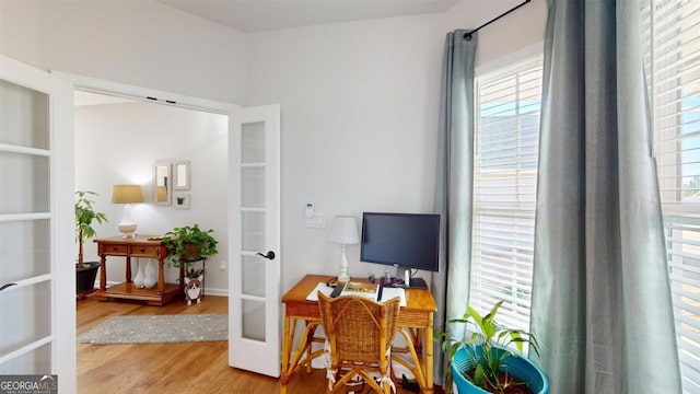 office with light wood-type flooring and french doors