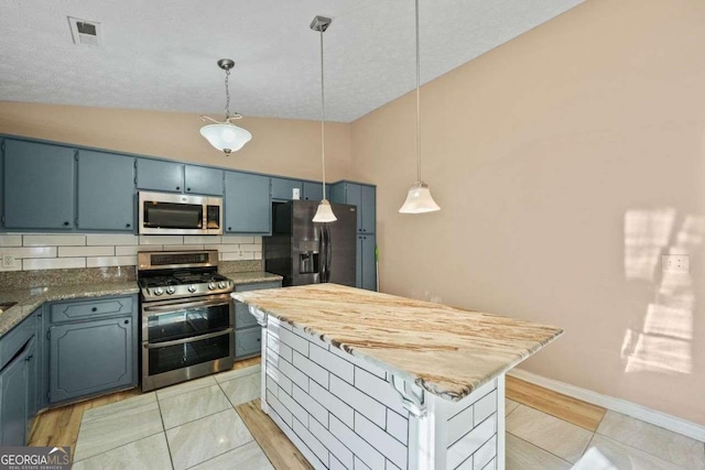 kitchen featuring a center island, blue cabinetry, stainless steel appliances, hanging light fixtures, and tasteful backsplash