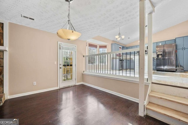 unfurnished dining area with dark hardwood / wood-style flooring, a chandelier, vaulted ceiling, and a textured ceiling