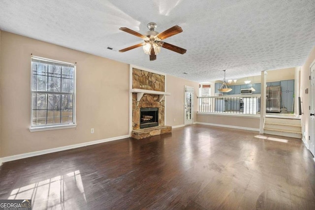 unfurnished living room with a textured ceiling, ceiling fan, dark hardwood / wood-style floors, and a stone fireplace