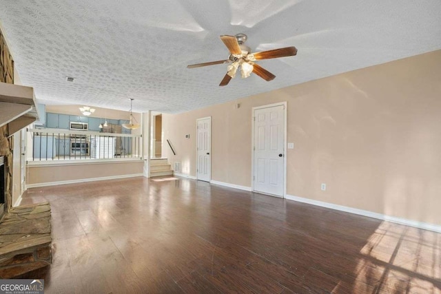 unfurnished living room with ceiling fan, dark wood-type flooring, a textured ceiling, and a fireplace