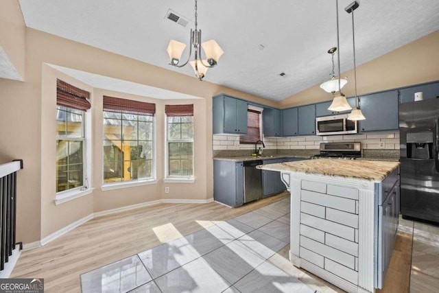 kitchen with blue cabinetry, appliances with stainless steel finishes, a center island, and decorative light fixtures