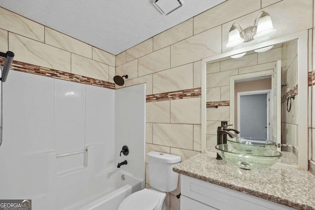 full bathroom featuring shower / bathing tub combination, toilet, a textured ceiling, tile walls, and vanity