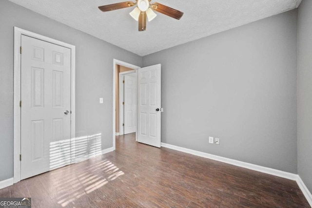 unfurnished bedroom with ceiling fan, dark hardwood / wood-style flooring, and a textured ceiling