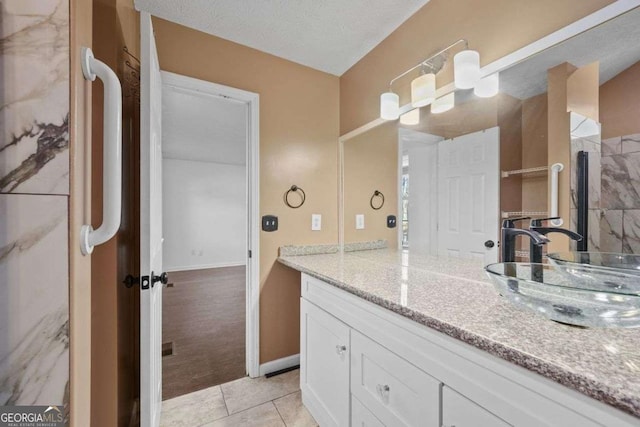 bathroom with a textured ceiling, tile patterned flooring, and vanity