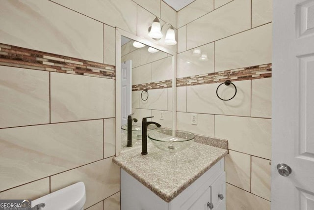 bathroom featuring toilet, tile walls, and vanity