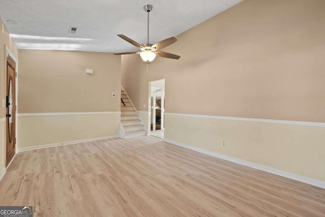 spare room featuring ceiling fan, light wood-type flooring, vaulted ceiling, and a textured ceiling