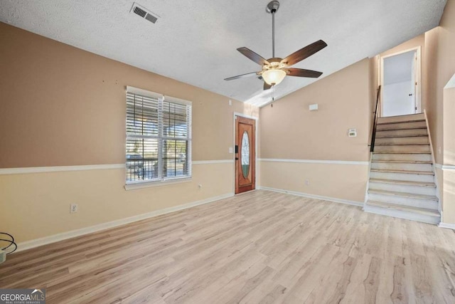 unfurnished living room featuring ceiling fan, light hardwood / wood-style flooring, a textured ceiling, and lofted ceiling