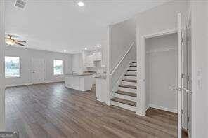 unfurnished living room featuring stairs and dark wood finished floors