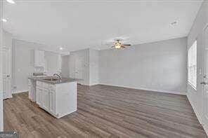 kitchen with dark wood-style floors, open floor plan, a center island with sink, and white cabinets