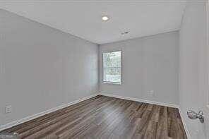 unfurnished room featuring dark wood-style flooring and baseboards