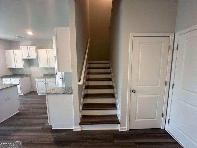 staircase featuring wood finished floors, visible vents, and baseboards