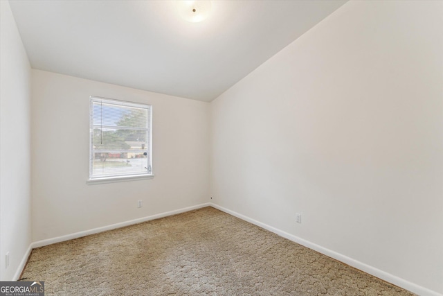 carpeted spare room featuring vaulted ceiling