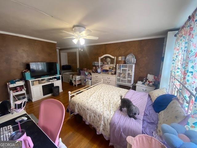 bedroom featuring dark hardwood / wood-style flooring, ceiling fan, and crown molding