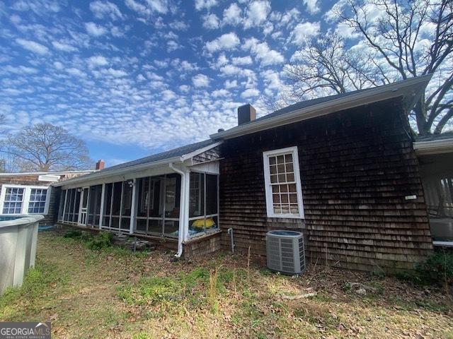 rear view of house featuring central AC unit and a sunroom