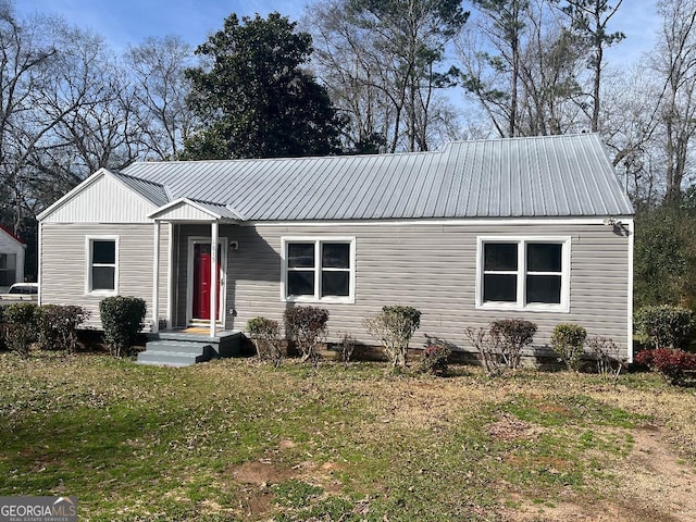 view of front of house featuring metal roof and a front yard