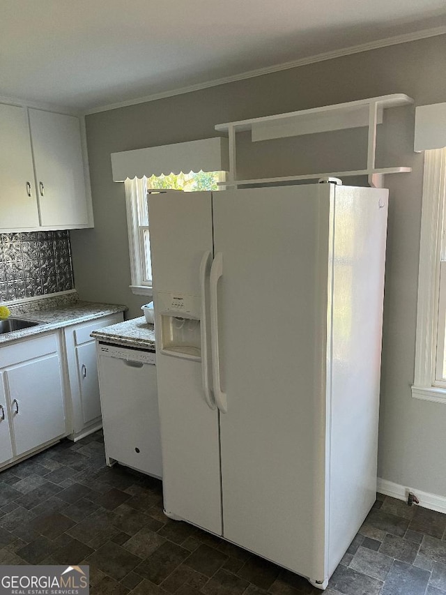 kitchen featuring white appliances, decorative backsplash, white cabinets, stone finish floor, and crown molding