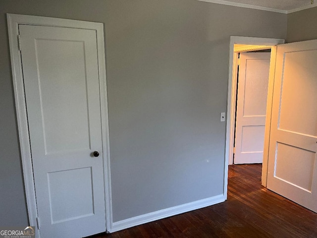 unfurnished bedroom featuring crown molding, baseboards, and dark wood-type flooring