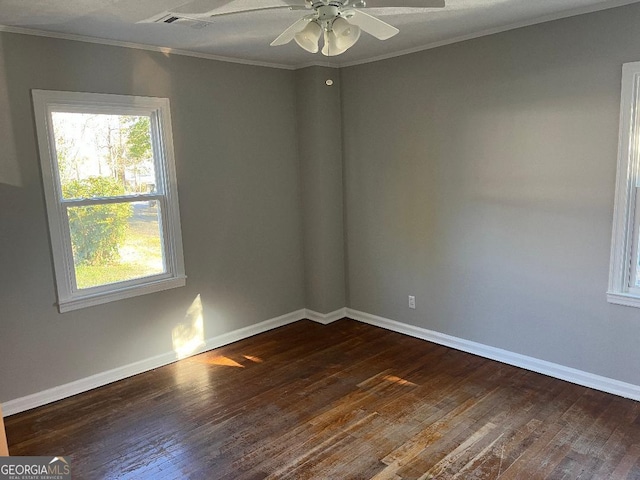 empty room with crown molding, visible vents, dark wood finished floors, and baseboards