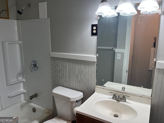 bathroom with  shower combination, wainscoting, vanity, and toilet