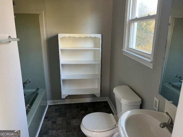 bathroom featuring a washtub, baseboards, a sink, and toilet