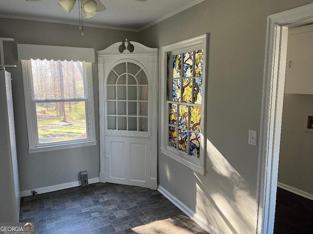 unfurnished dining area with stone finish floor, baseboards, a ceiling fan, and ornamental molding