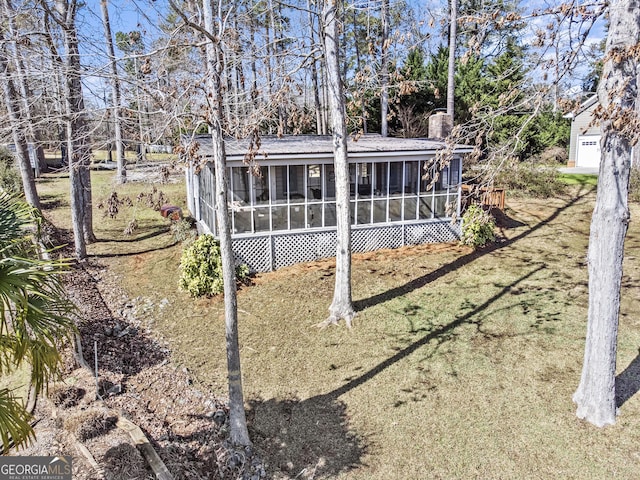 rear view of house featuring a sunroom and a lawn