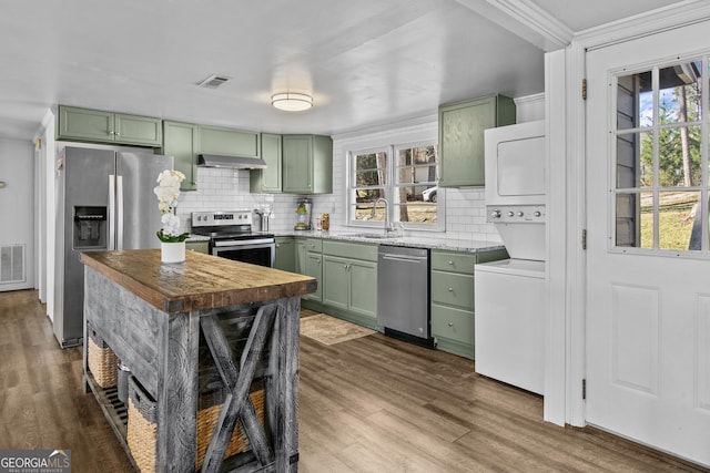 kitchen featuring appliances with stainless steel finishes, sink, dark wood-type flooring, green cabinetry, and stacked washer and dryer