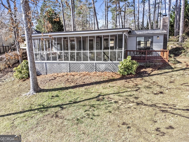 back of house featuring a yard, a wooden deck, and a sunroom