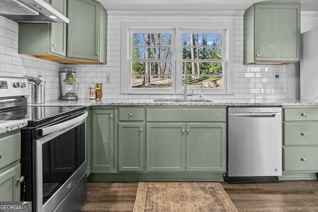 kitchen featuring green cabinets, range hood, sink, light stone counters, and appliances with stainless steel finishes