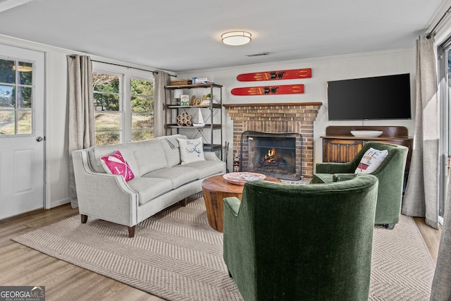 living room with crown molding, a brick fireplace, and hardwood / wood-style floors