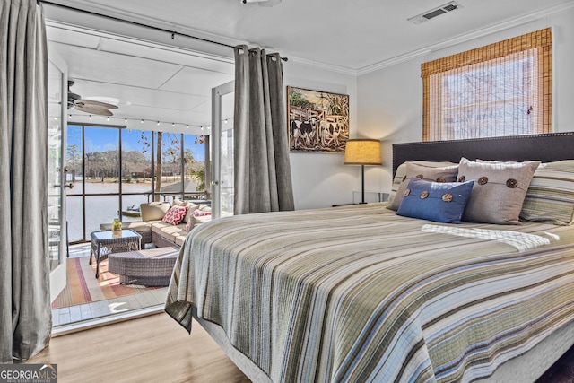 bedroom featuring hardwood / wood-style floors, a water view, expansive windows, access to exterior, and ornamental molding