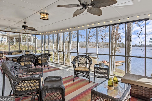 sunroom with ceiling fan and a water view