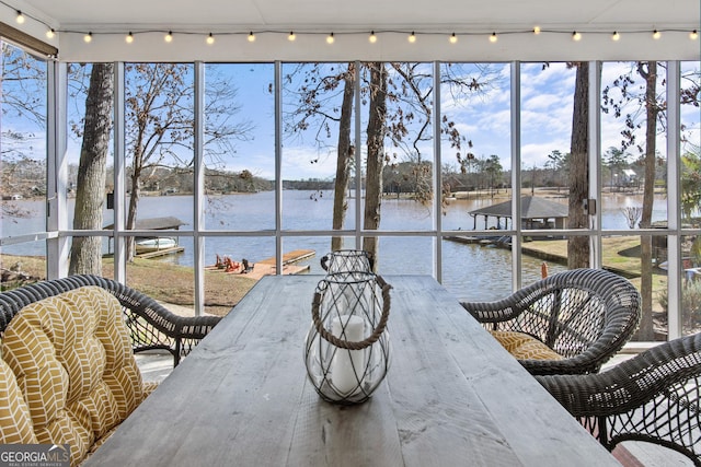 sunroom featuring a water view and track lighting