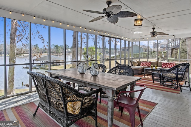 sunroom with a water view and ceiling fan