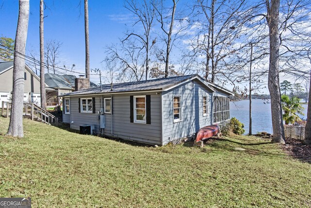 view of side of home with a water view, cooling unit, and a lawn