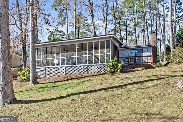 back of house with a deck, a yard, and a sunroom