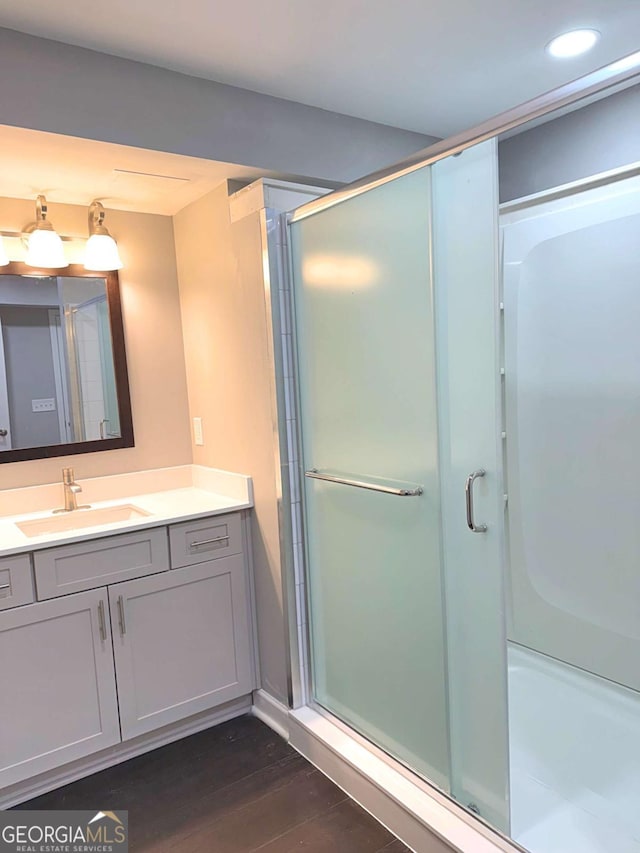 bathroom featuring vanity, wood-type flooring, and a shower with shower door