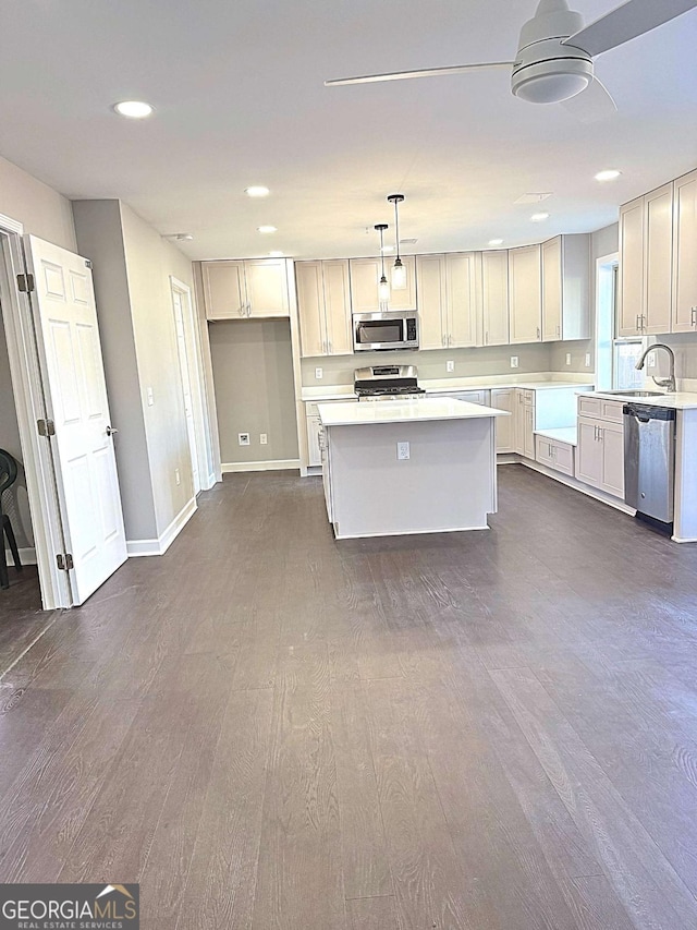 kitchen with stainless steel appliances, decorative light fixtures, a kitchen island, white cabinetry, and dark hardwood / wood-style floors