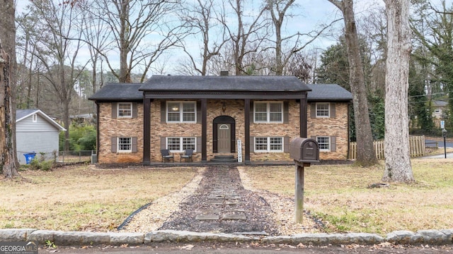 bi-level home with brick siding, a front yard, and fence