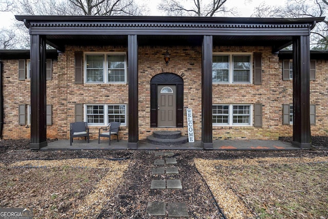 bi-level home featuring entry steps, brick siding, and a patio