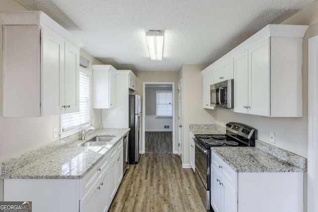 kitchen featuring sink, stainless steel appliances, white cabinetry, and light stone counters