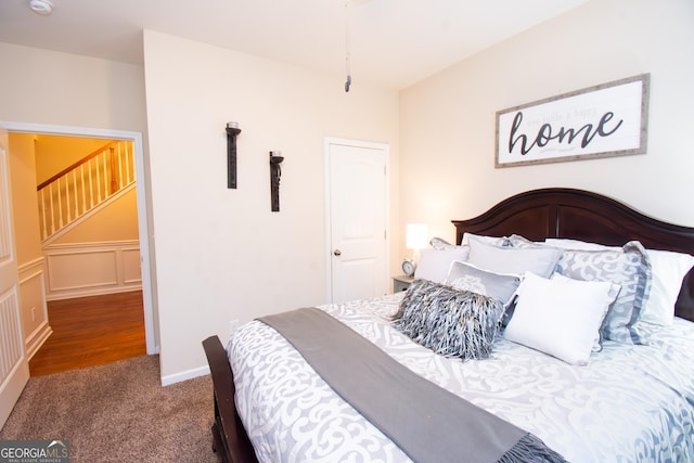 bedroom featuring a wainscoted wall, a decorative wall, and carpet flooring