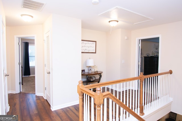 corridor featuring attic access, baseboards, visible vents, dark wood-type flooring, and an upstairs landing