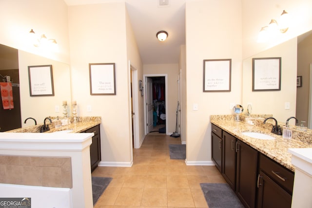 full bath featuring tile patterned flooring, vanity, baseboards, and a spacious closet