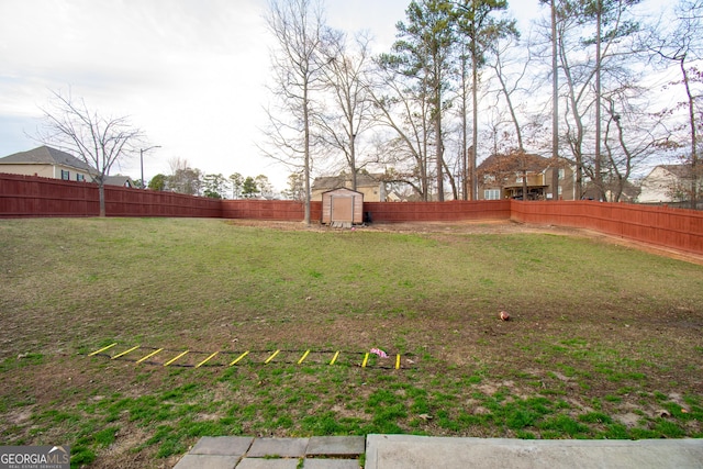 view of yard featuring an outbuilding, a fenced backyard, and a storage unit